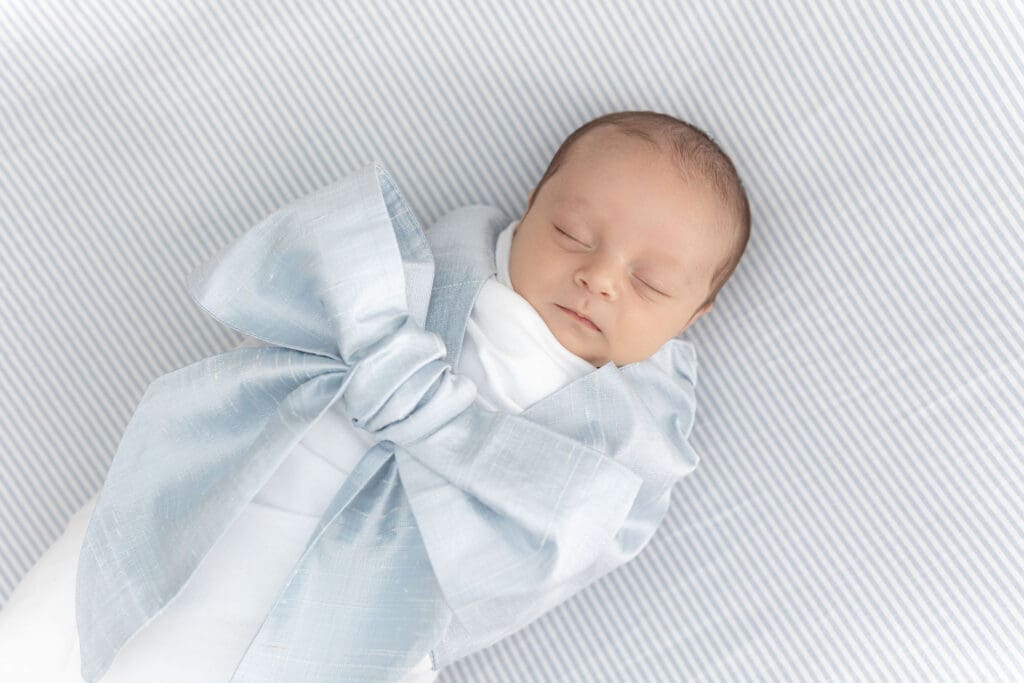 Louisville KY newborn photographer capturing sleeping baby wrapped in blue bow wrap