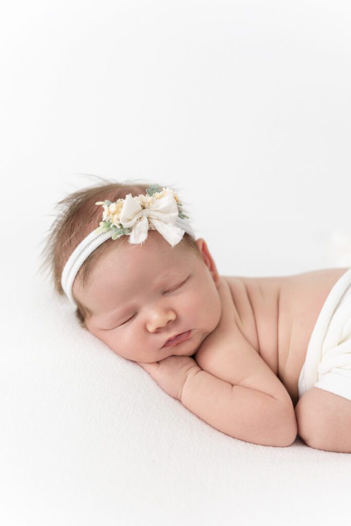 Sleeping newborn girl wearing floral headband during a studio newborn photography session in Louisville, KY