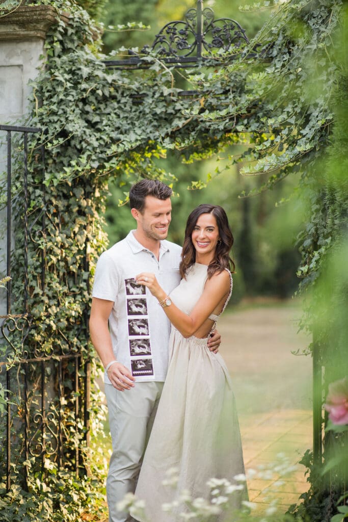 Louisville pregnancy announcement photo session at Whitehall House and Gardens iron garden gate with ultrasound photos