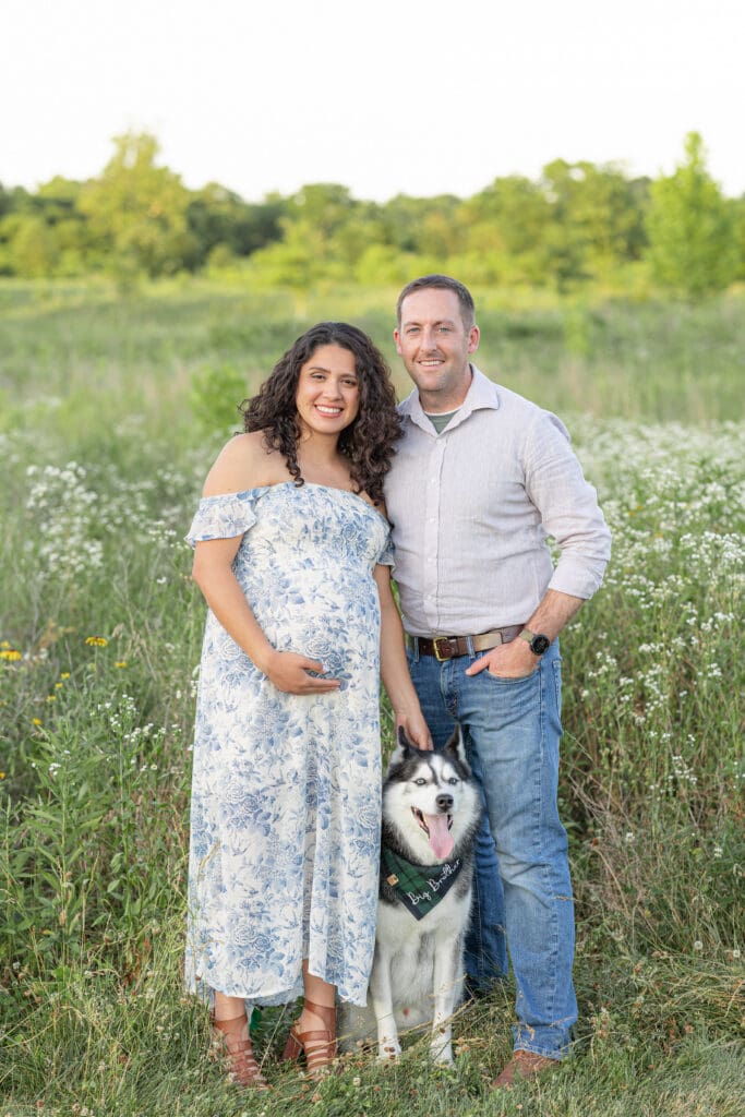 outdoor maternity photography Beckley Creek Park Louisville KY couple with husky dog standing in wildflower field at sunset