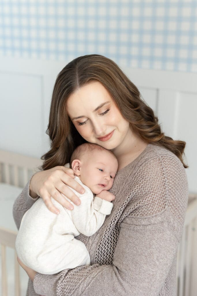 lifestyle newborn photographer Louisville KY mother smiling down at sleeping newborn baby boy in home session